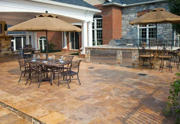 A patio with tables and chairs and umbrellas in front of a house.