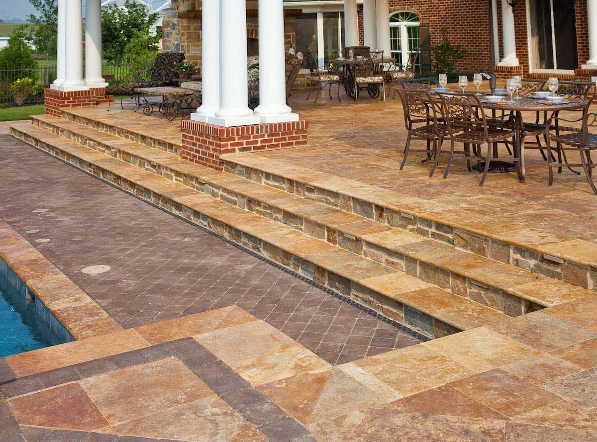 A patio with tables and chairs next to a swimming pool.