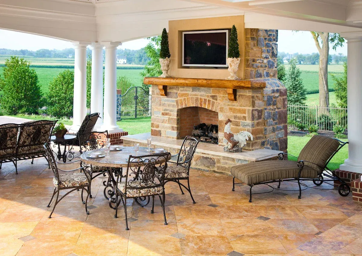 A patio with a fireplace and a television on the wall.