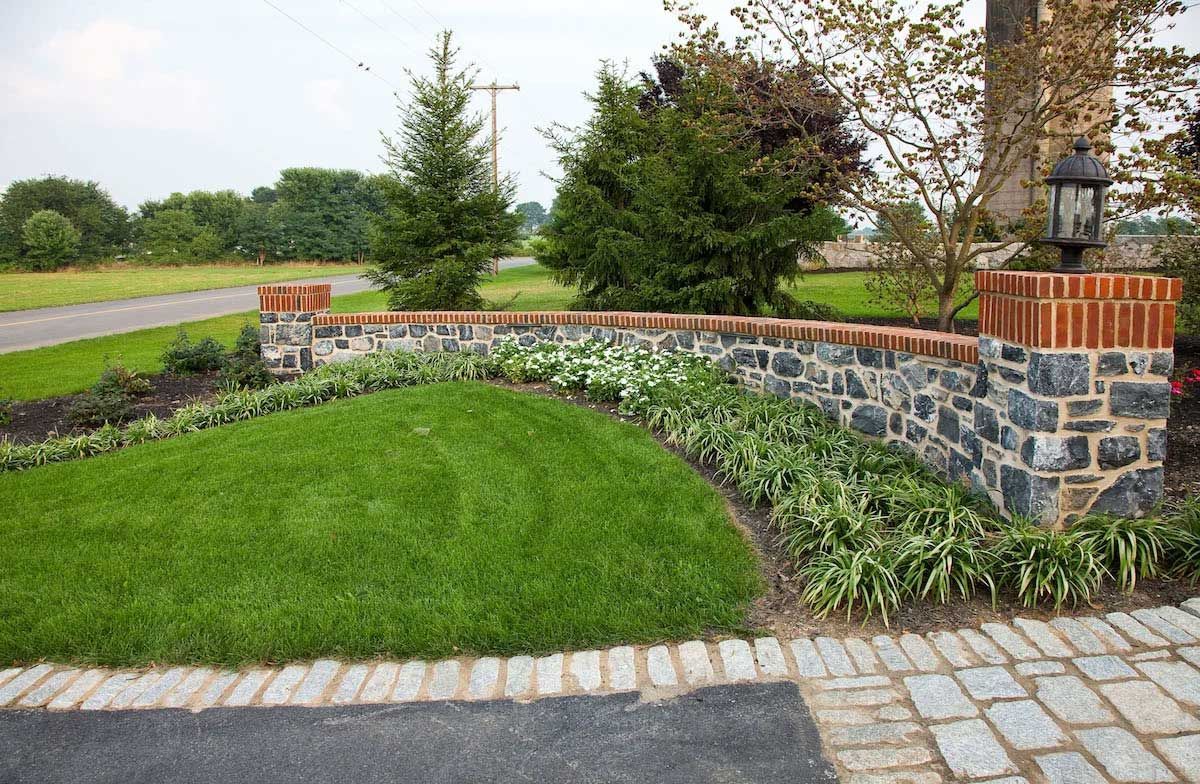 A stone wall is surrounded by a lush green lawn.