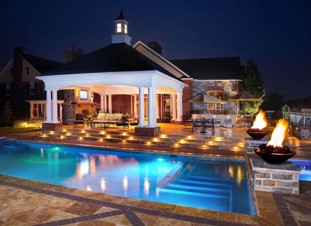 A large swimming pool with a gazebo in the background at night