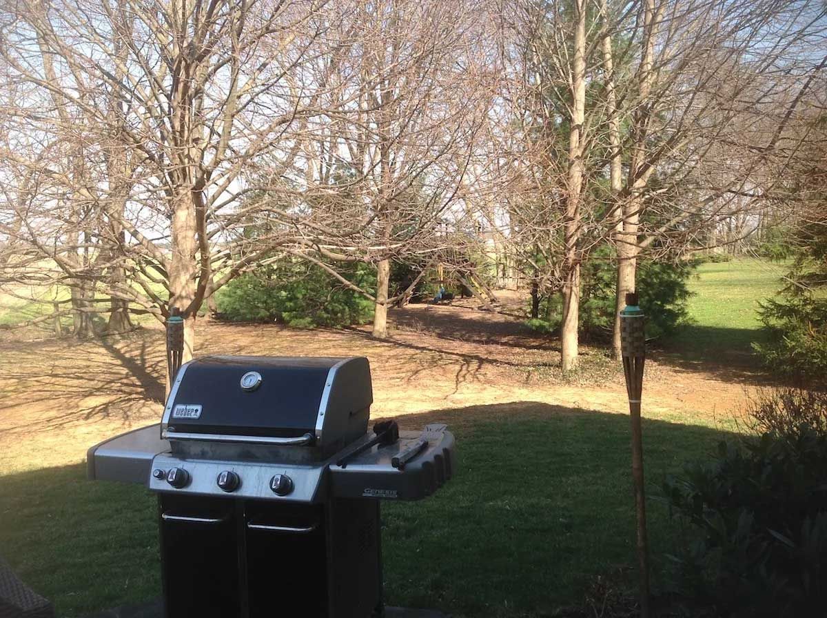 A black grill is sitting in the middle of a lush green field.