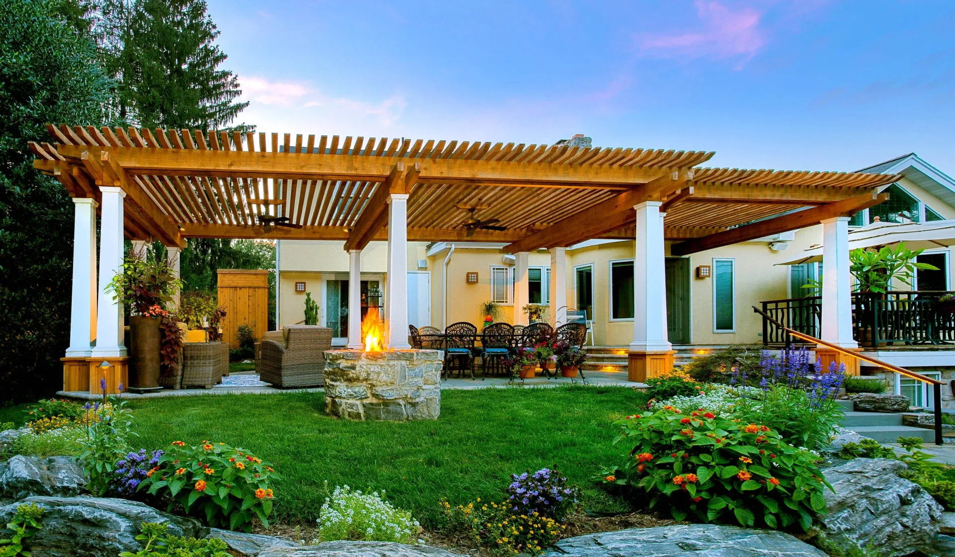 A house with a pergola and a fire pit in the backyard.