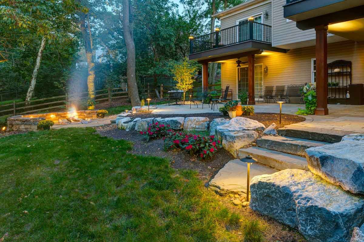 A patio with a table and chairs on it in front of a house.