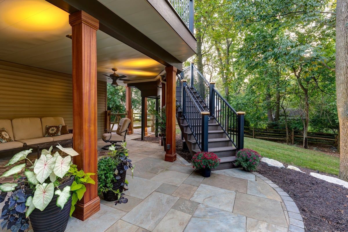 A patio with stairs leading up to a deck and a porch.