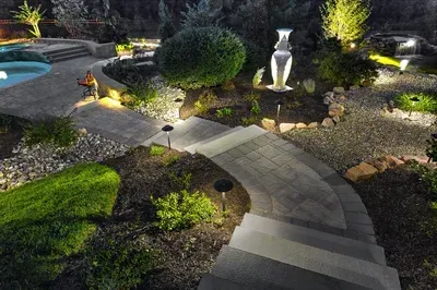 A walkway leading to a pool is lit up at night.