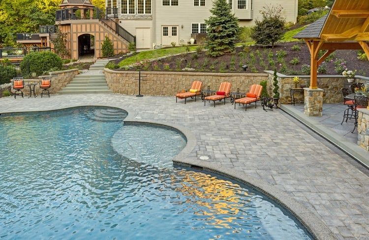 There is a large swimming pool in the backyard of a house.