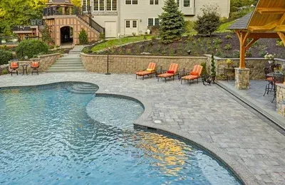 There is a large swimming pool in the backyard of a house.