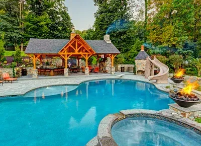 A large swimming pool with a slide and a fire pit in the backyard.