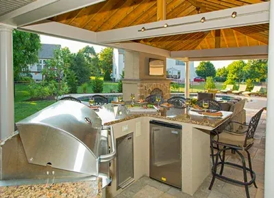 A kitchen with stainless steel appliances and granite counter tops under a wooden roof.