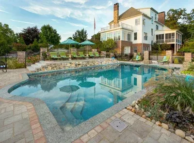 There is a large swimming pool in the backyard of a house.