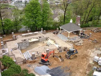 An aerial view of a construction site with a pool and gazebo in the background.
