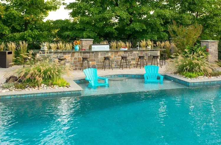 There are two blue chairs in the middle of the pool.