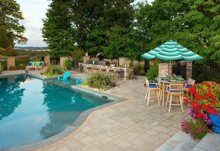 A large swimming pool with a table and chairs and an umbrella.