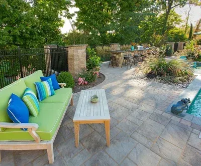 A patio with a green couch and a table next to a pool