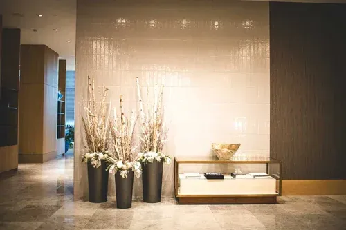 Hotel lobby with large vases of decorative branches, modern furniture, and a marble floor.