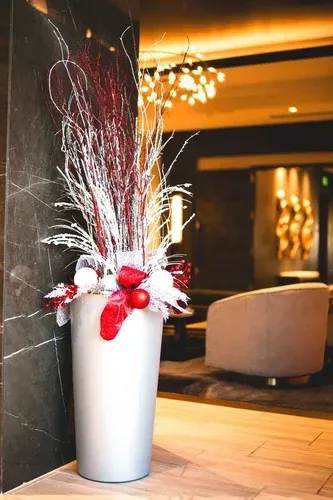 Silver vase with red and white floral arrangement in an elegant lobby.