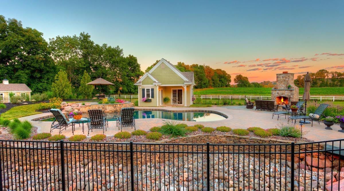 A house with a pool and a fireplace in the backyard behind a fence.