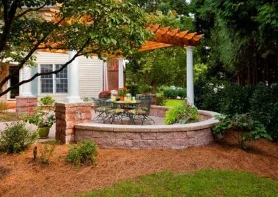 A patio with a table and chairs under a pergola in front of a house.