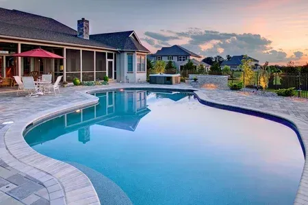 There is a large swimming pool in the backyard of a house.