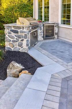A patio with a grill and a refrigerator on it.