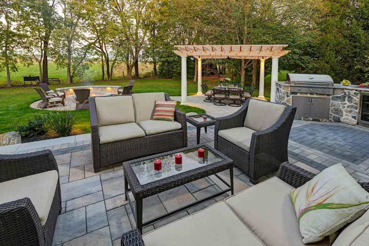 A patio with a couch , chairs , a table and a pergola.