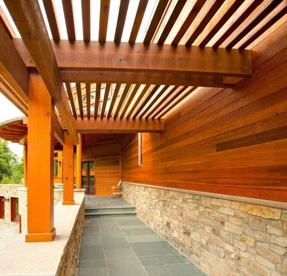 A wooden walkway leading to a house with a stone wall