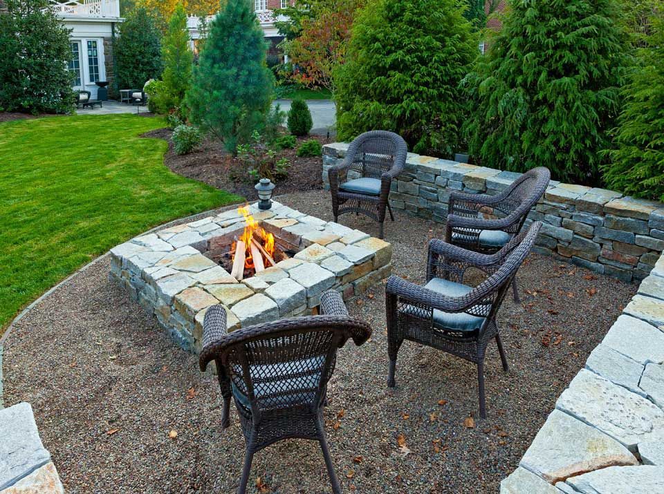 A fire pit with chairs around it in a backyard.