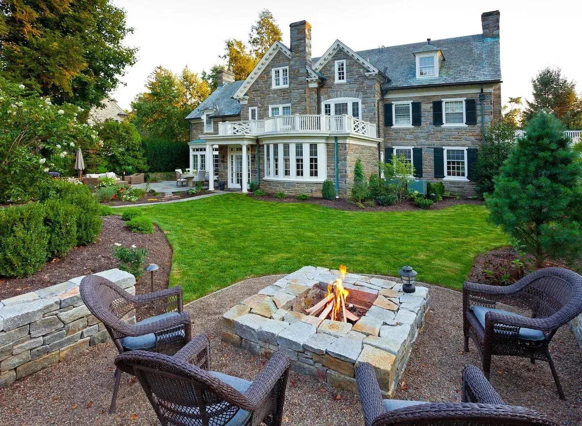 There is a fire pit in the backyard of a large house.