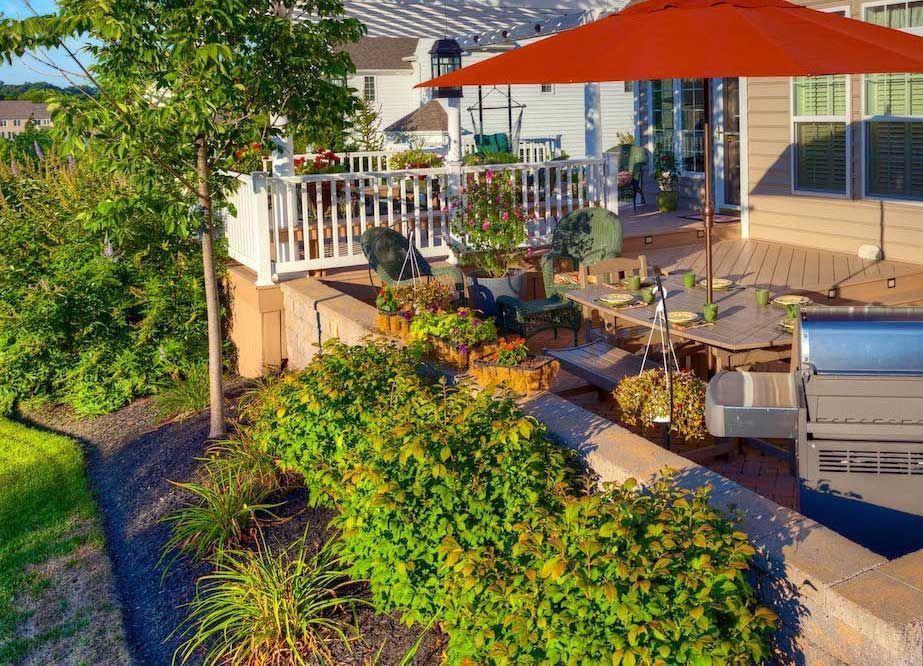 An aerial view of a patio with a red umbrella and a grill.