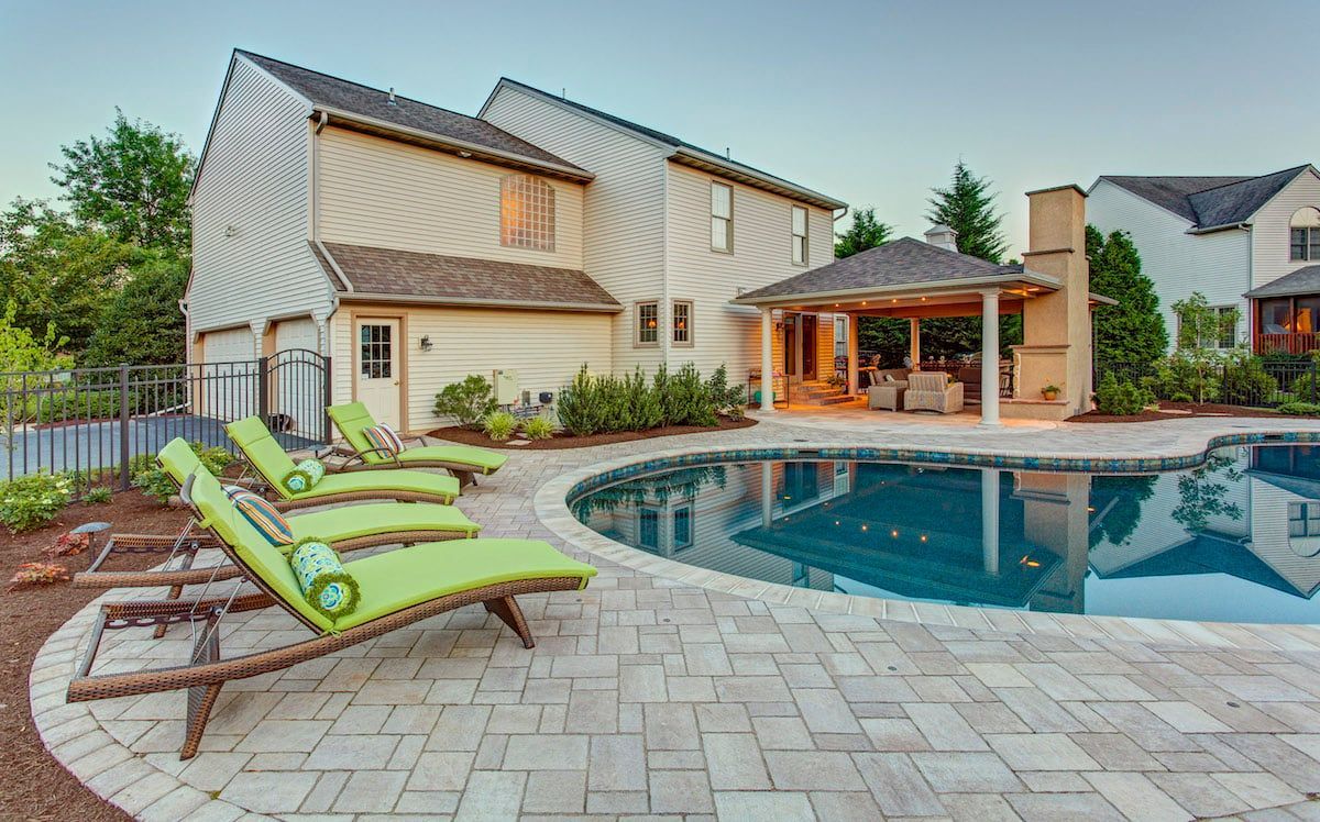 There is a large swimming pool in the backyard of a house.