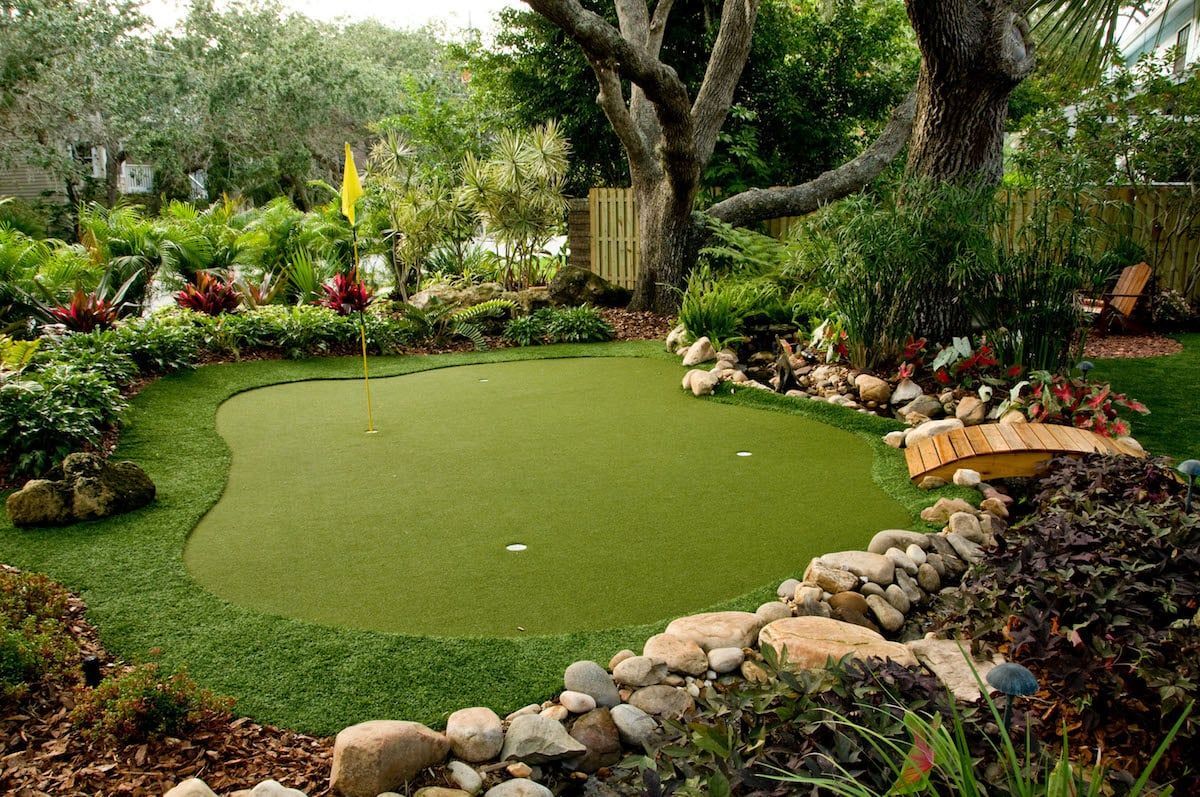 A putting green in a garden surrounded by rocks and trees