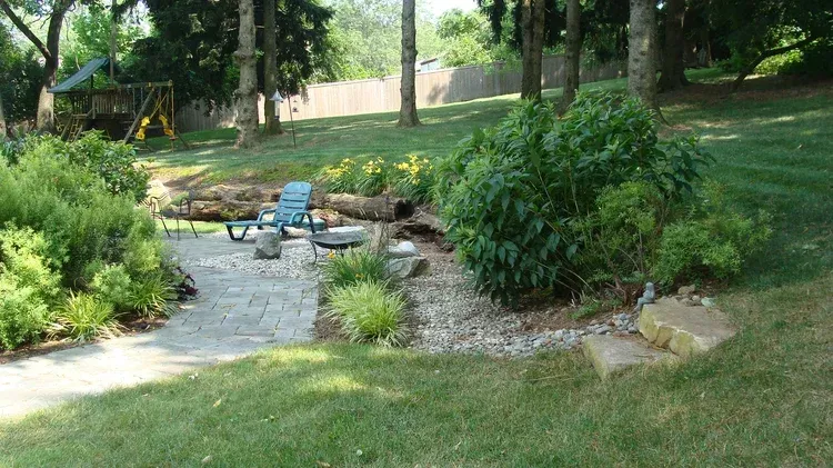 A backyard with a patio and a swing set in the background.