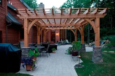 A wooden pergola is in the backyard of a house