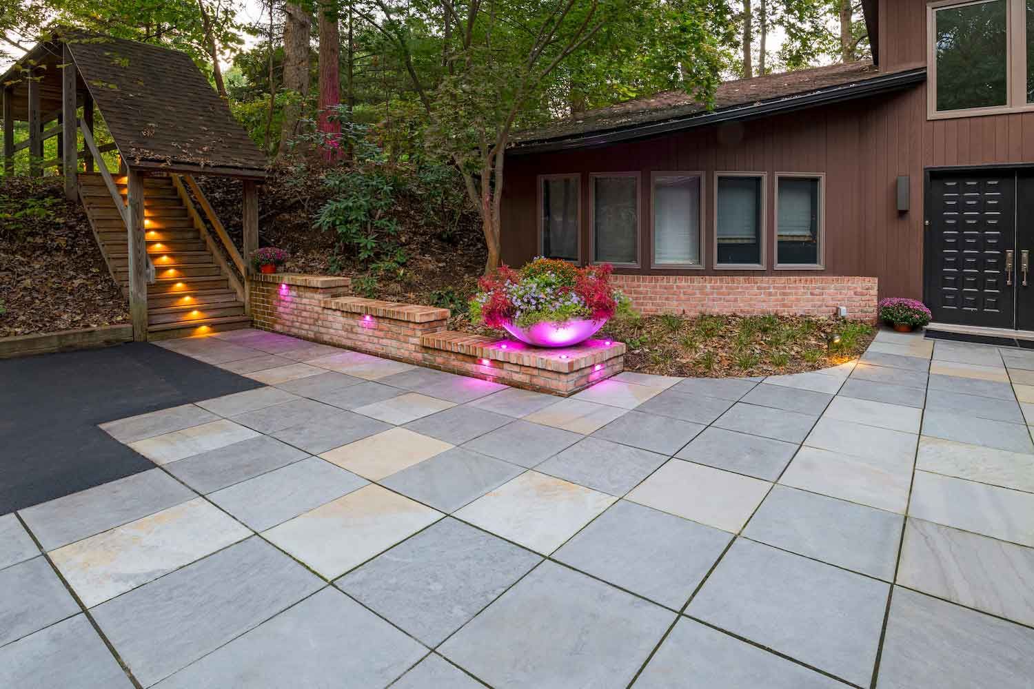 A patio with a table and chairs on it in front of a house.