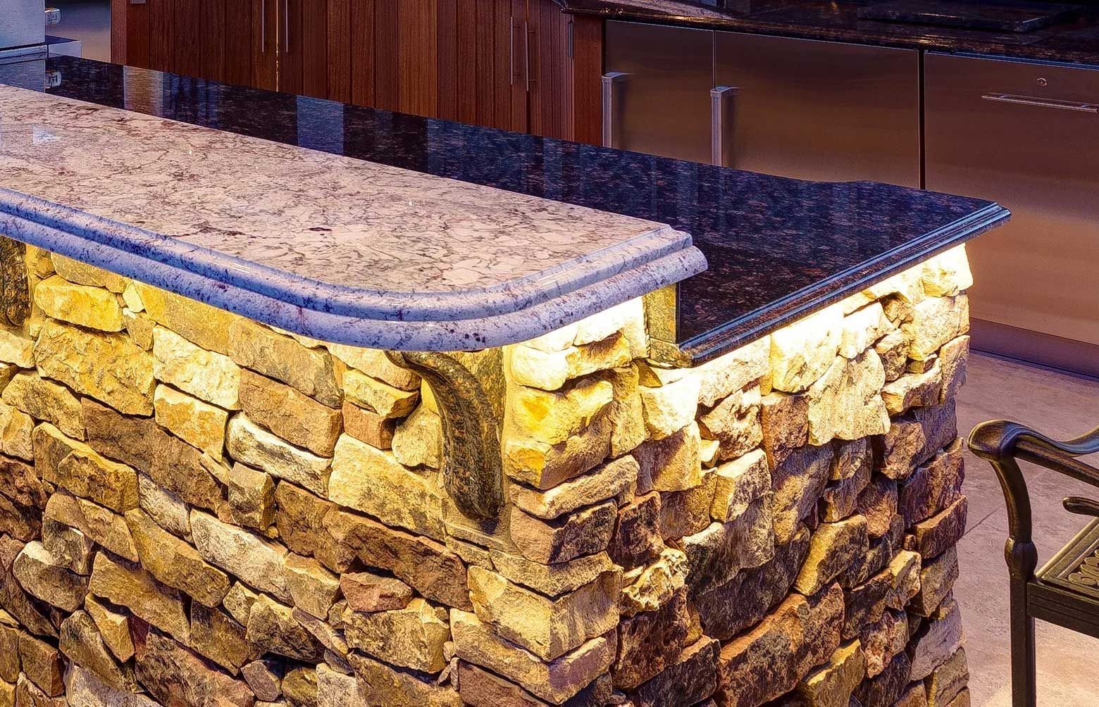 A kitchen with a stone counter top and a chair.