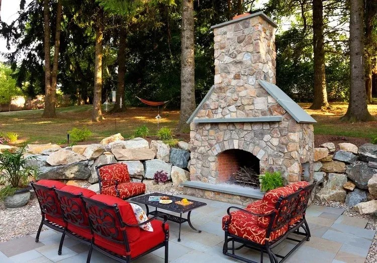 A patio with a fireplace and a couch and chairs