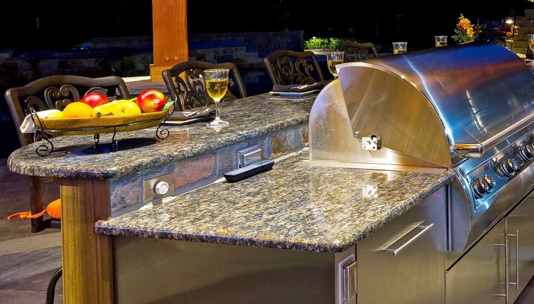 A stainless steel grill is sitting on top of a granite counter top.