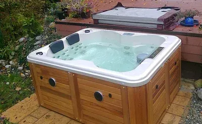 A wooden hot tub is sitting next to a wooden deck.