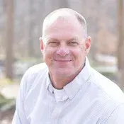A man in a white shirt is smiling for the camera.