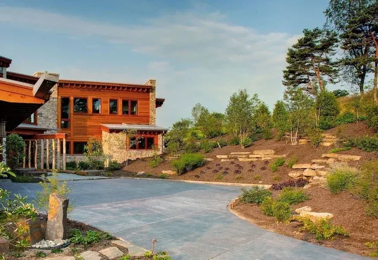 A large house is sitting on top of a hill with a driveway leading to it.