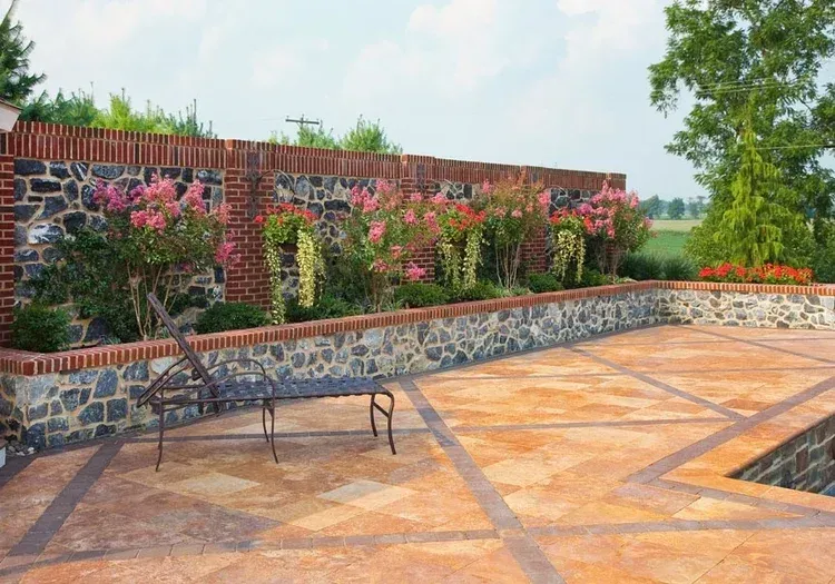A brick wall surrounds a patio with a table and chairs.