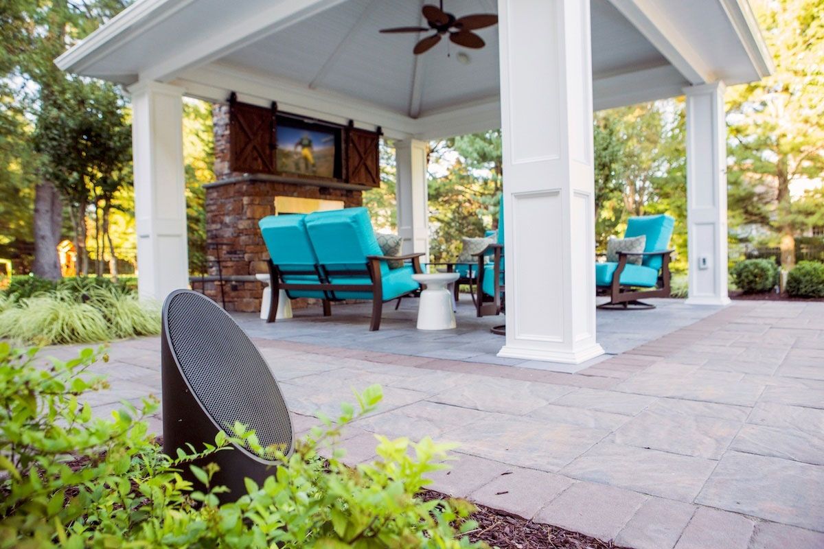 A patio with a table and chairs on it in front of a house.