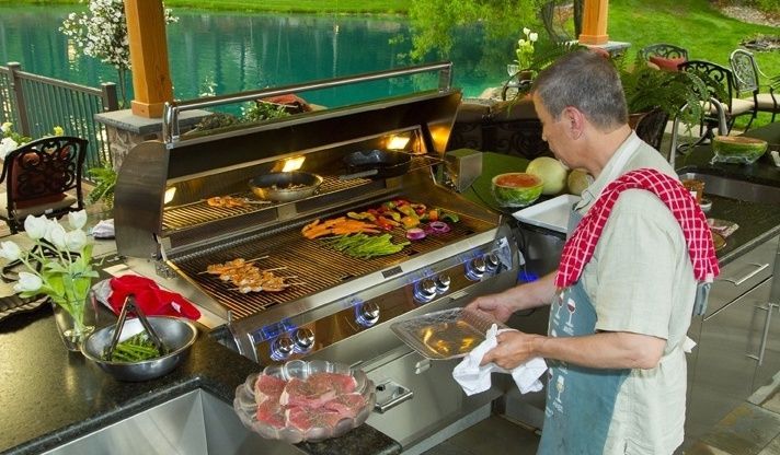 A man is cooking food on a grill in an outdoor kitchen.