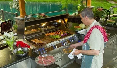 A man is cooking food on a grill in an outdoor kitchen.