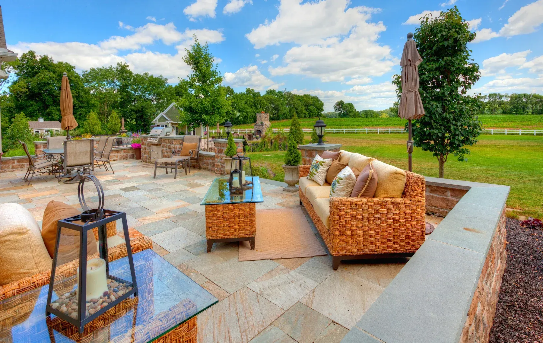 A patio with a couch , table , chairs and umbrellas.