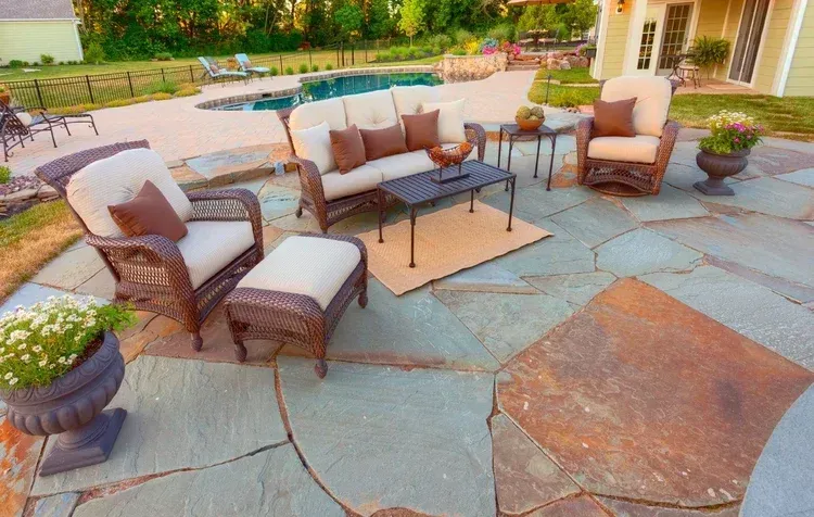 A patio with furniture and a pool in the background