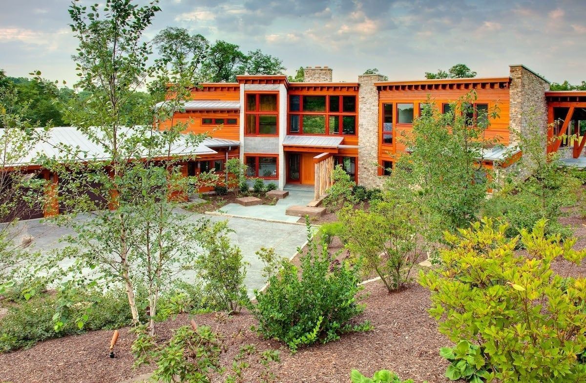 A large orange house is surrounded by trees and bushes.
