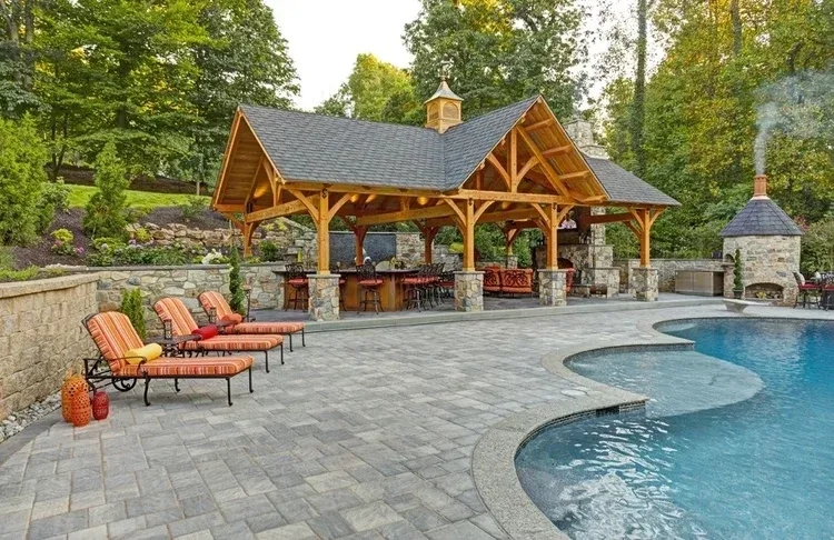 A large swimming pool with a pavilion and chairs around it