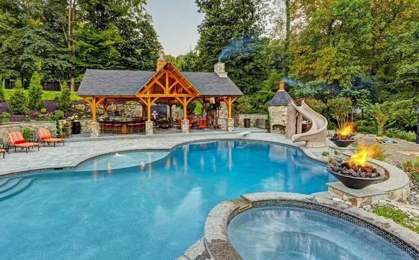 A large swimming pool with a slide and a fire pit in the backyard.